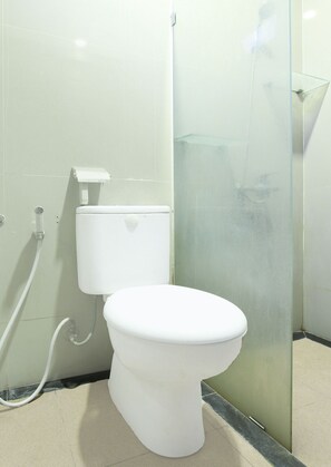 A modern bathroom with a white toilet, a glass shower enclosure, and a visible toilet paper holder. - Hotel O Rumah Daun Guesthouse Jogja (Yogyakarta)