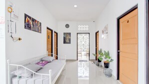 A hotel room with a bed, a desk, and a chair. There is a window and a door. - Hotel O Rumah Daun Guesthouse Jogja (Yogyakarta)