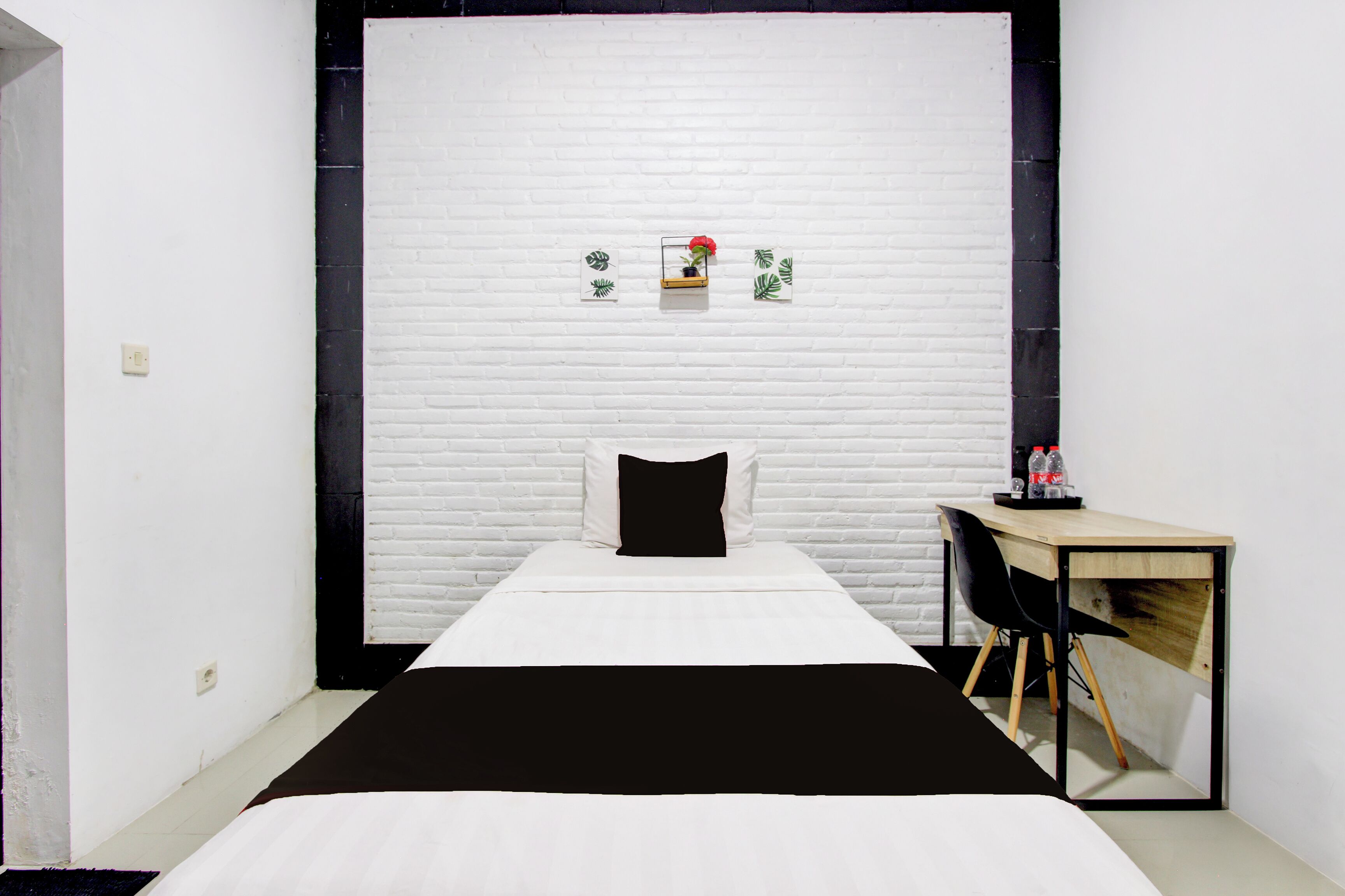 A minimalist room with a bed, a desk, and a white brick wall.
