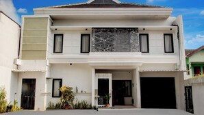 A two-story house with a symmetrical facade, a central entrance, and a garage. - Hotel O Rumah Daun Guesthouse Jogja (Yogyakarta)