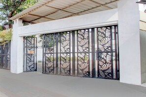 A modern building with a white exterior and a metal gate with a leaf pattern. - Hotel O Rumah Daun Guesthouse Jogja (Yogyakarta)