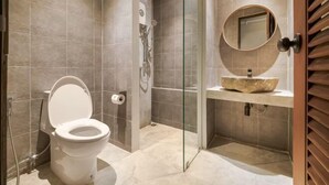 A modern bathroom with a toilet, shower, and sink.