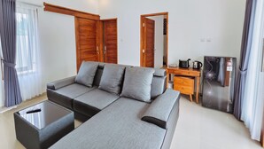 Een moderne woonkamer met een hoekbank, een salontafel, een houten kast en een koelkast.