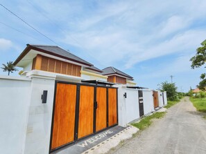 A modern house with a white exterior, a wooden door, and a welcome mat. - Bali Lovina Karuna Villa (kayu Putih)