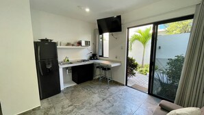 A compact kitchen with a refrigerator, microwave, and sink. There is a bar stool and a television mounted on the wall. - Lavish Studio w Kitchen Downtown 1 (Isla Mujeres)