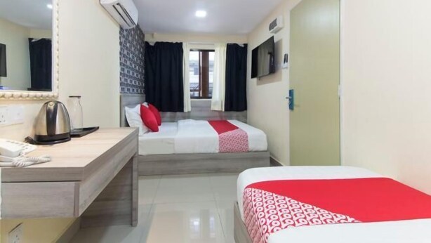 Une chambre d’hôtel avec deux lits, un bureau doté d’un téléphone et d’une bouilloire, un miroir et un téléviseur fixé au mur.