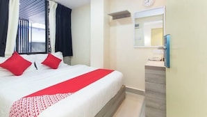 Une chambre d’hôtel avec un lit, une literie rouge et blanche, une table de chevet, un miroir et une horloge au mur.