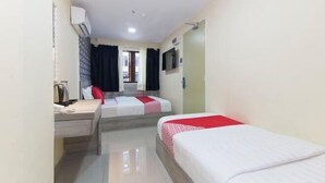Une chambre d’hôtel avec deux lits, un bureau, une chaise, un appareil de climatisation et un téléviseur.