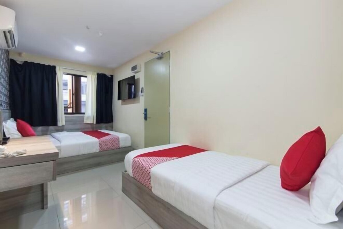 Habitación de hotel con dos camas, un escritorio, un espejo y un televisor.