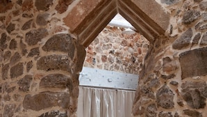 Ein Korridor mit Steinwänden und einer kleinen Treppe, die zu einem Raum mit weißem Vorhang führt.