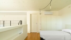 Een slaapkamer met twee bedden, een witte kast en een balkon met een hekwerk.