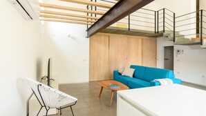 Een moderne woonkamer met een blauwe bank, een witte stoel en een houten salontafel.