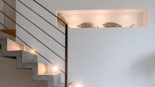 Een moderne trap met geïntegreerde verlichting, een witte muur en een minimalistisch ontwerp.