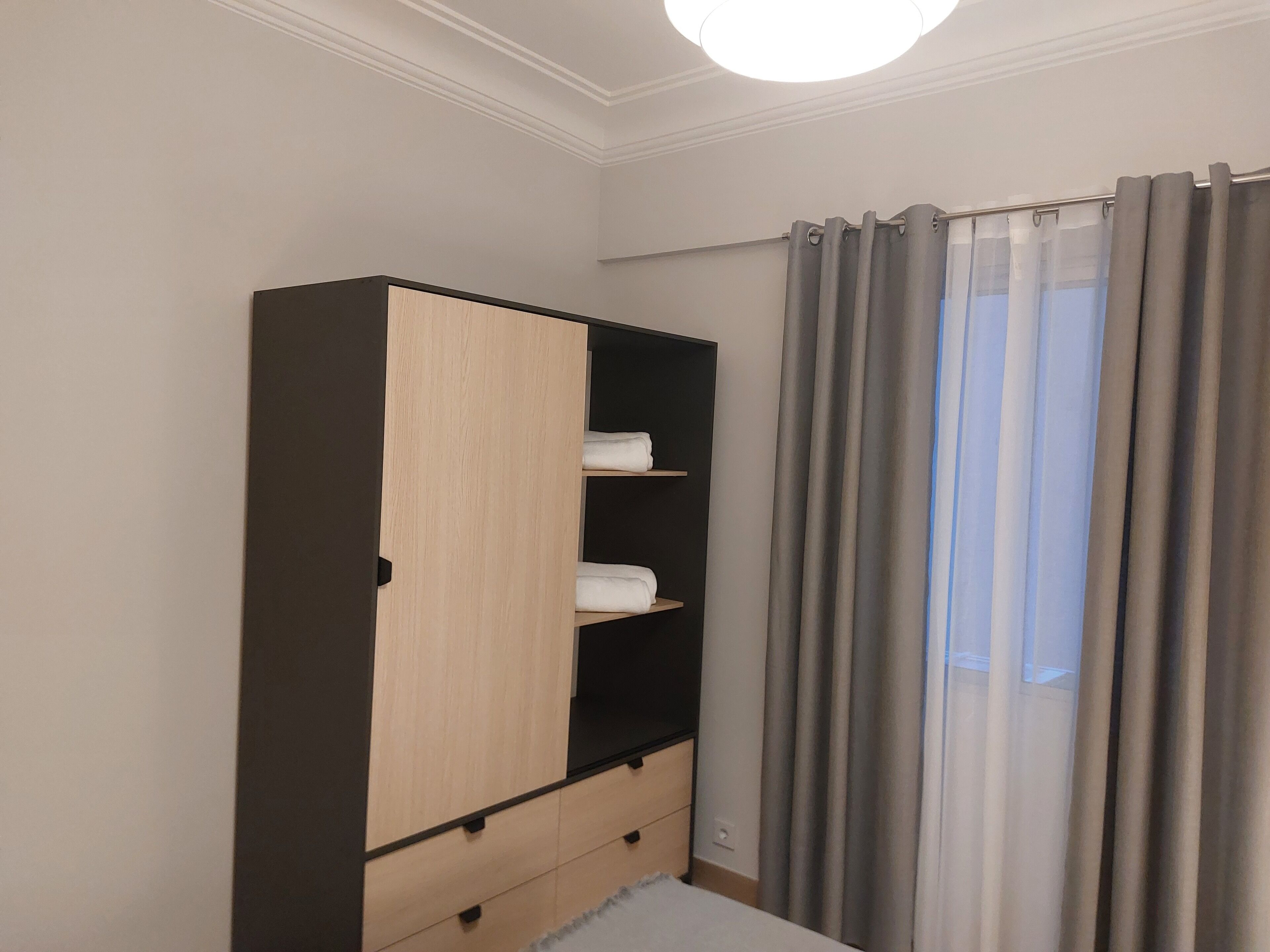 Une chambre à coucher avec un placard, un lit et une fenêtre avec des rideaux.