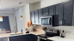 Una cocina moderna con armarios oscuros, un lavavajillas de acero inoxidable, un microondas y una estufa.