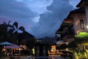 Un resort con piscina, zona de estar al aire libre y una entrada bien iluminada.