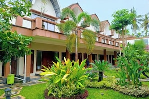 A hotel with a covered outdoor area, palm trees, and a well-maintained garden. - Melati Resort & Hotel Kuta Lombok (Pujut)