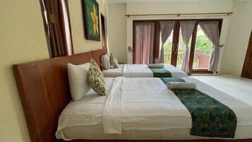 A hotel room with two beds, a wooden headboard, a large window with curtains, and a painting on the wall.