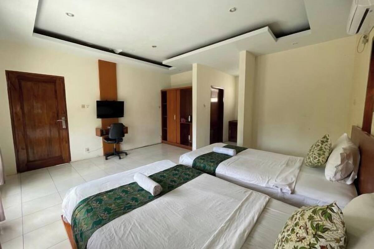 A hotel room with two beds, a TV, a desk, and a wardrobe.