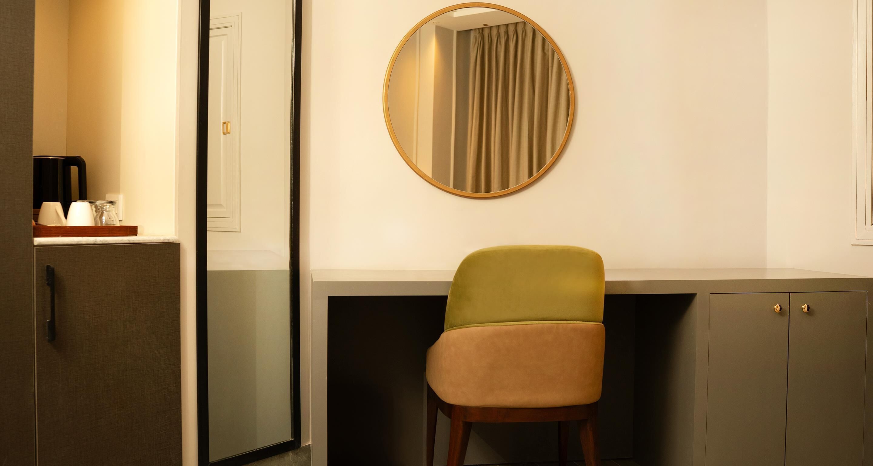 A room with a desk, a chair, a mirror, and a cabinet.