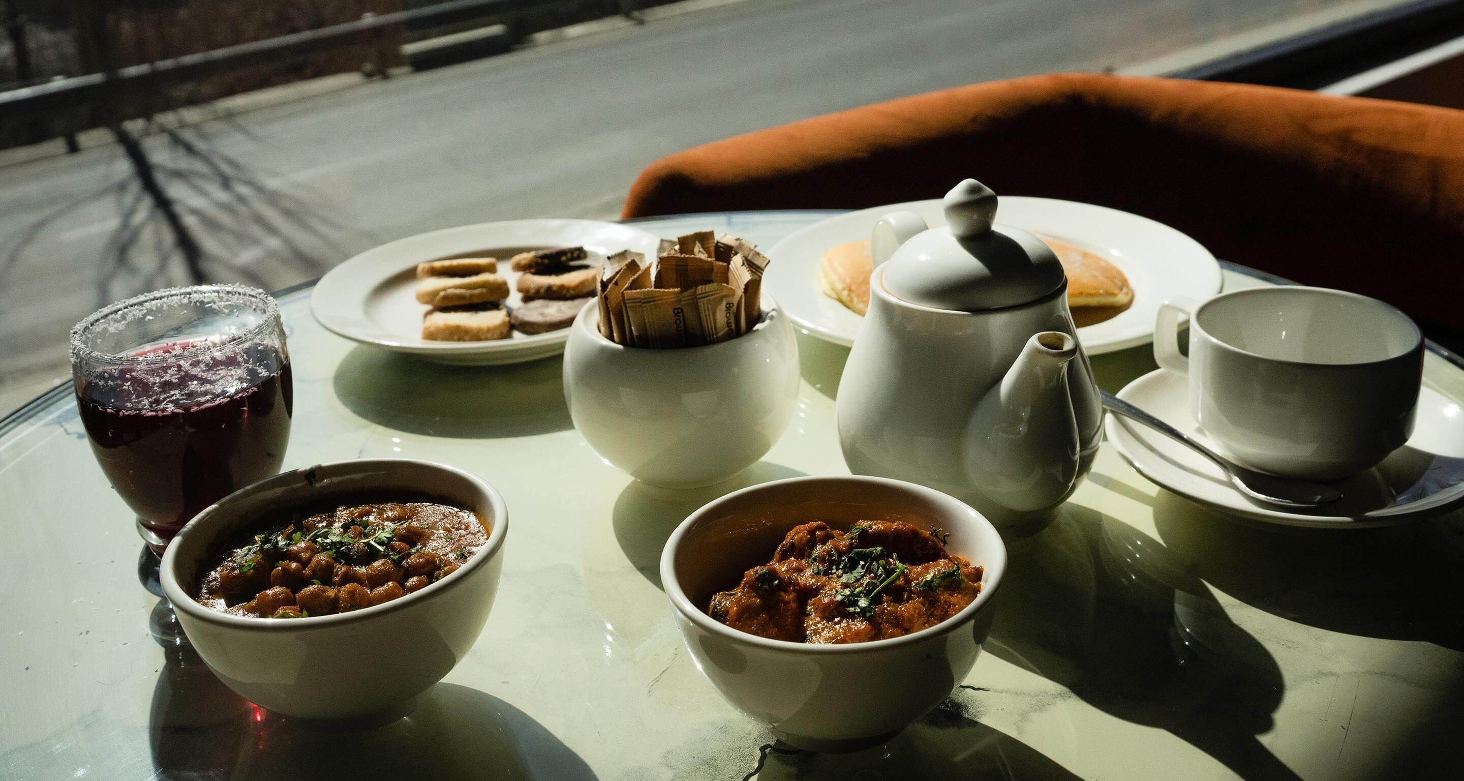 Una mesa con diversos platos, incluyendo tazones de comida y una tetera, en un día soleado.
