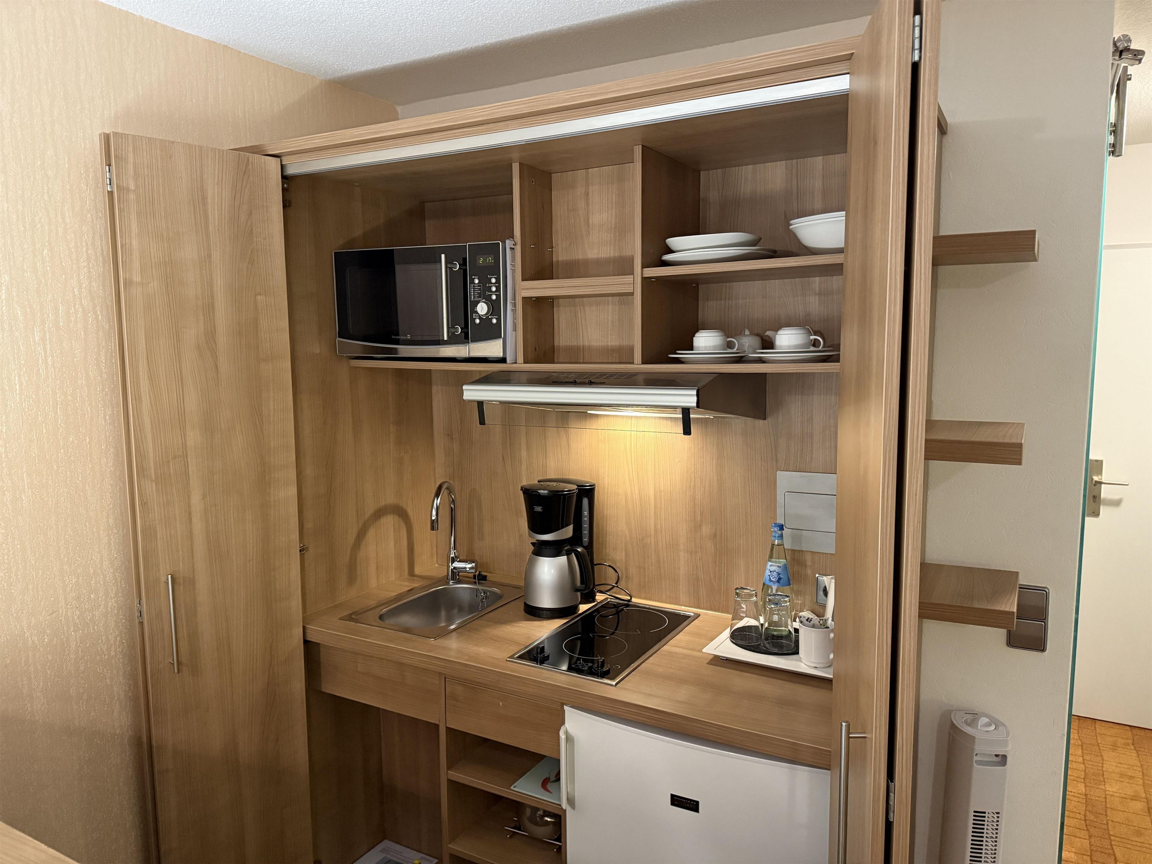Una cocina compacta equipada con microondas, cafetera y un refrigerador pequeño.
