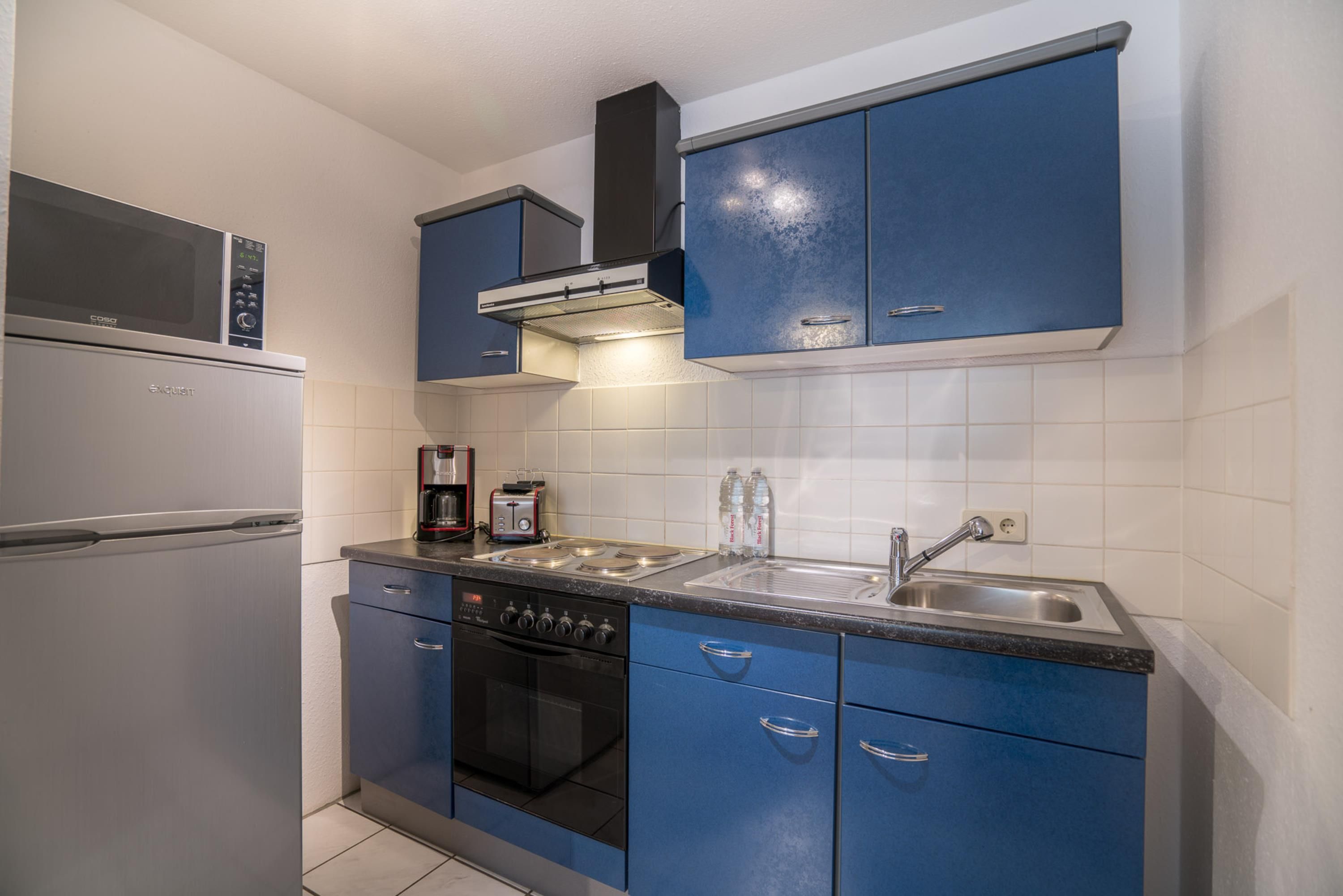 A compact kitchen with a microwave, stove, oven, and a sink.