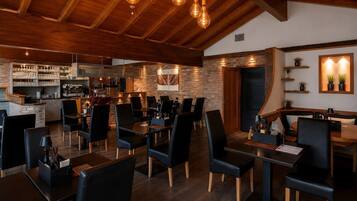 A restaurant with wooden beams, brick walls, and black leather chairs.