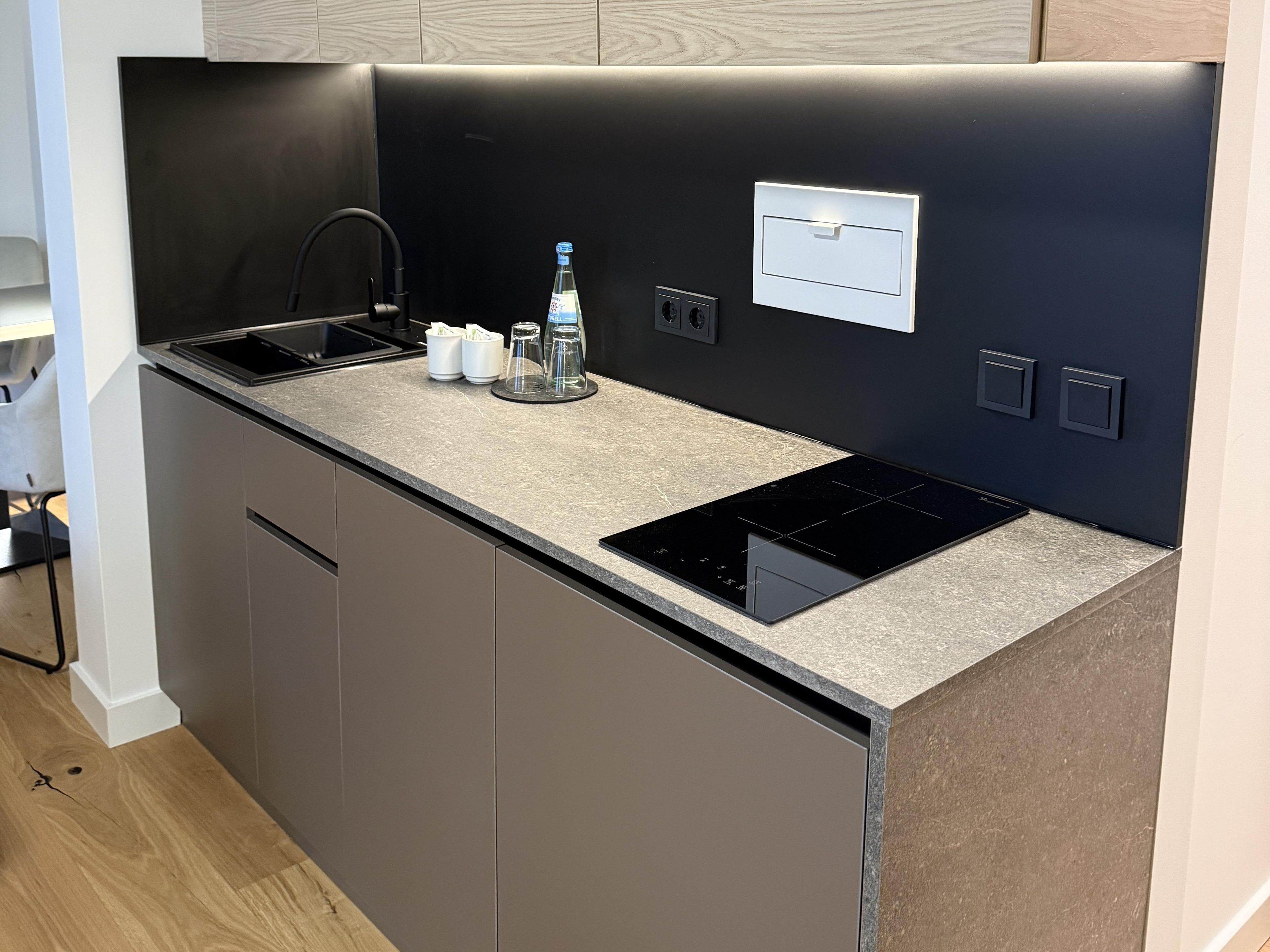 A modern kitchen with a built-in stove, a sink, and a countertop with salt and pepper shakers.