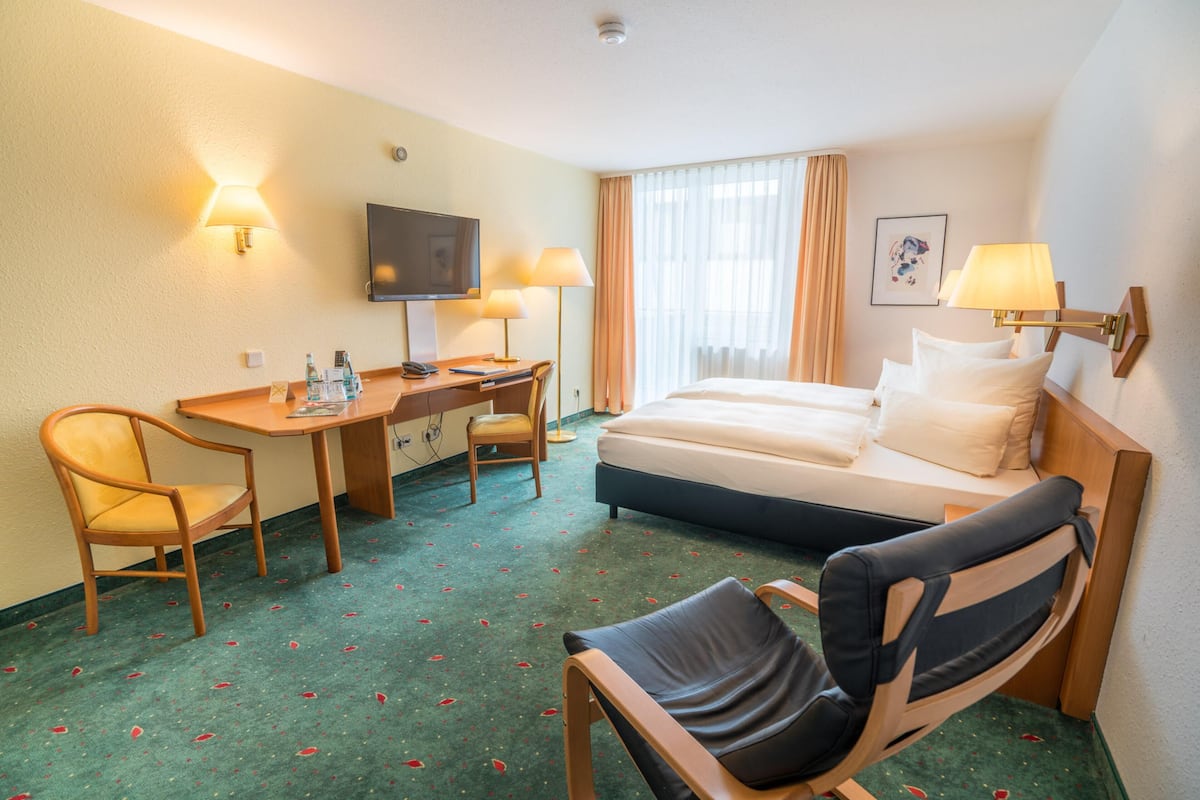 Une chambre d’hôtel équipée d’un lit, d’un bureau, de chaises et d’un téléviseur.