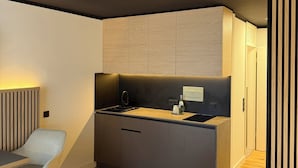 A modern bedroom with a bed, a small kitchenette, and a seating area. - Residenzhotel Stuttgart Airport, Sure Hotel Collection by BW (Steinenbronn)