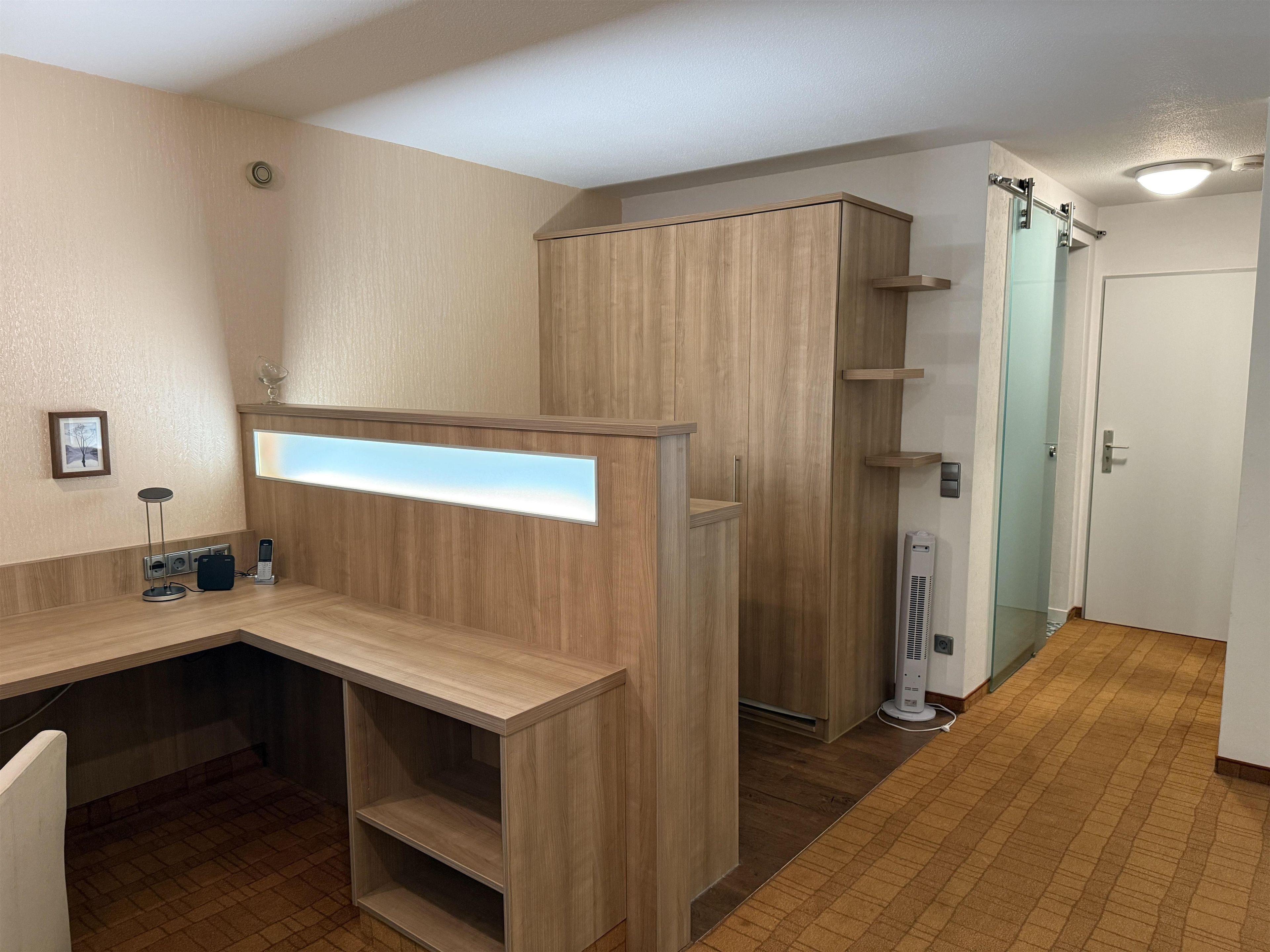A modern bathroom with a wooden vanity, a glass shower enclosure, and a white door.
