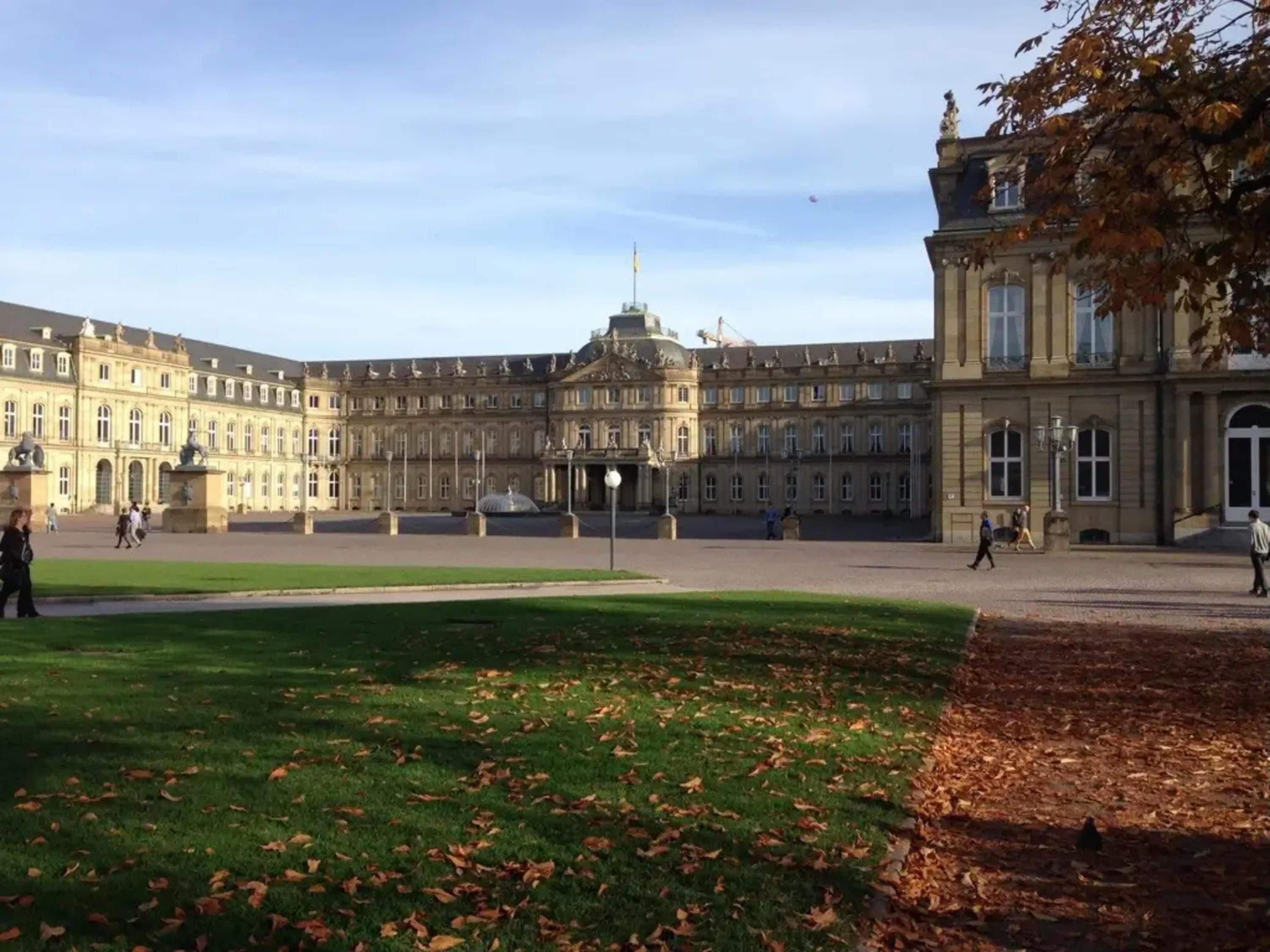 A large, historic building with a symmetrical facade, a central dome, and a spacious courtyard.