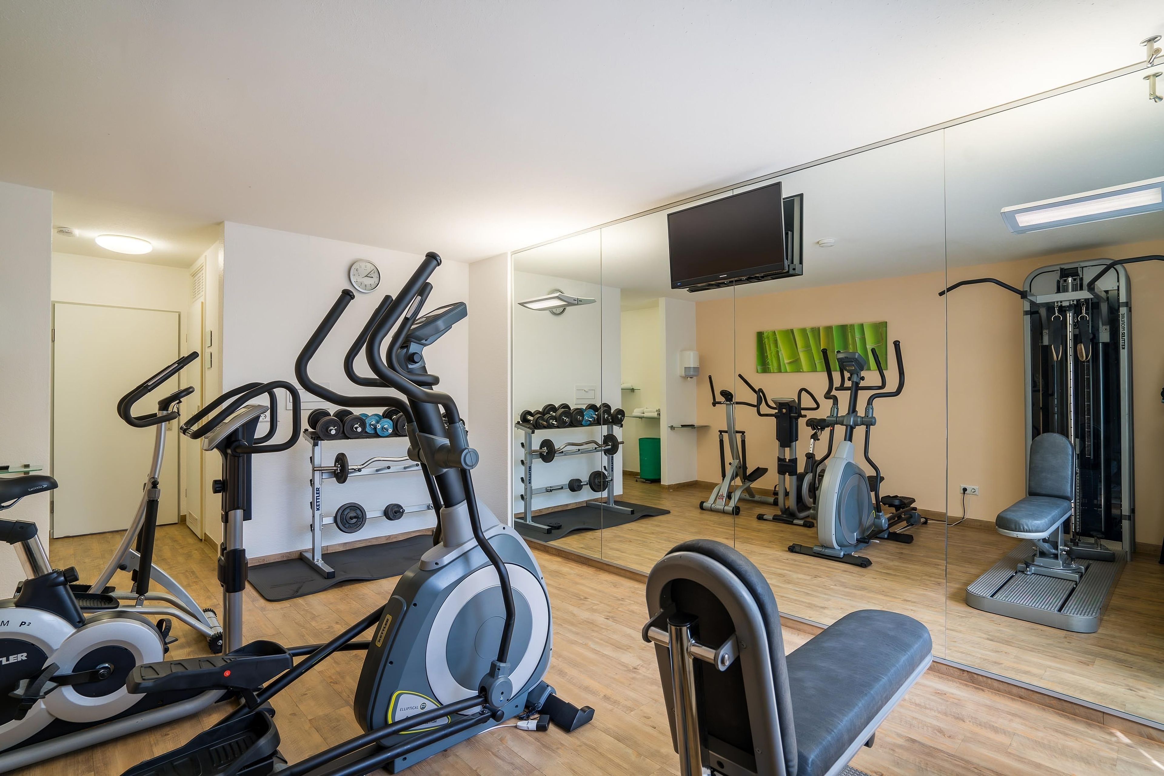 Un gimnasio con diversos equipos de ejercicio, incluyendo cintas de correr, bicicletas estáticas y máquinas de pesas.