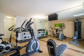 Un gimnasio con diversos equipos de ejercicio, incluyendo cintas de correr, bicicletas estáticas y máquinas de pesas.