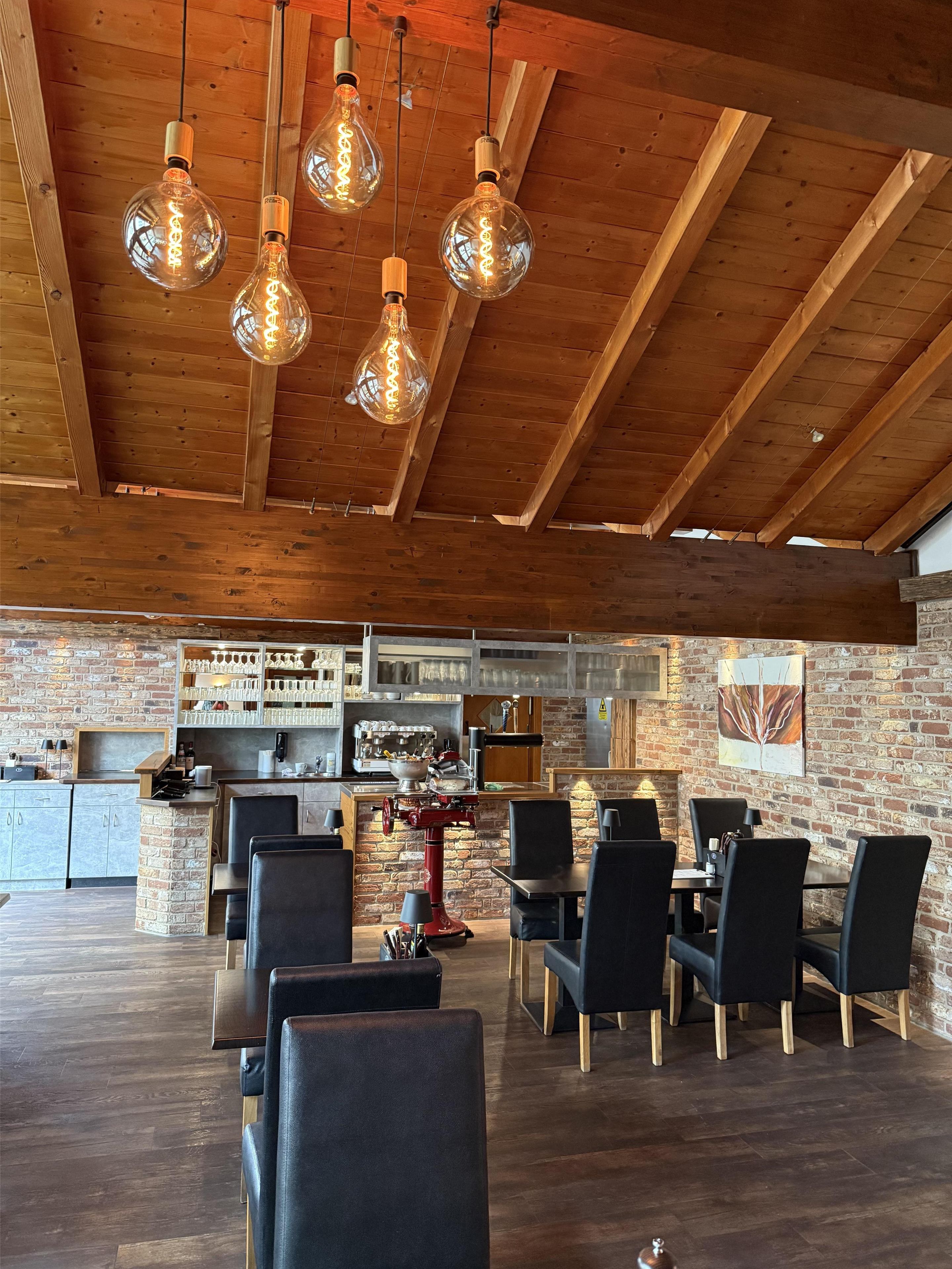 A spacious dining area with wooden beams and hanging light fixtures.