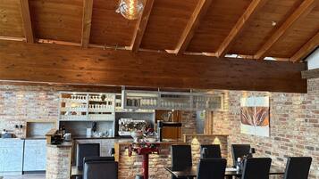 A spacious dining area with wooden beams and hanging light fixtures.
