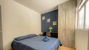 Une chambre à coucher avec un lit, un bureau, une chaise et une fenêtre.