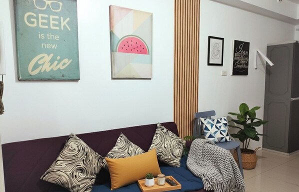 Uma sala de estar moderna com um sofá azul, almofadas estampadas e uma bandeja com uma planta.