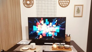 A dining area with a TV, a candle, and a small table with a cup and a bowl. - Mall of Asia - Cheap Accommodations (Pasay)