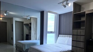 Une chambre moderne avec un grand miroir, deux lits, une armoire et une vue sur la mer.