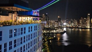 Un hôtel moderne doté d’une terrasse sur le toit offrant une vue panoramique sur la ville et sur un plan d’eau.