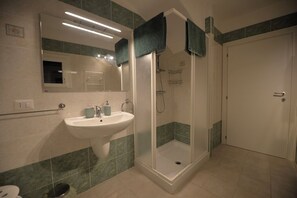 Ein Badezimmer mit Waschbecken, Spiegel, Dusche und Tür.