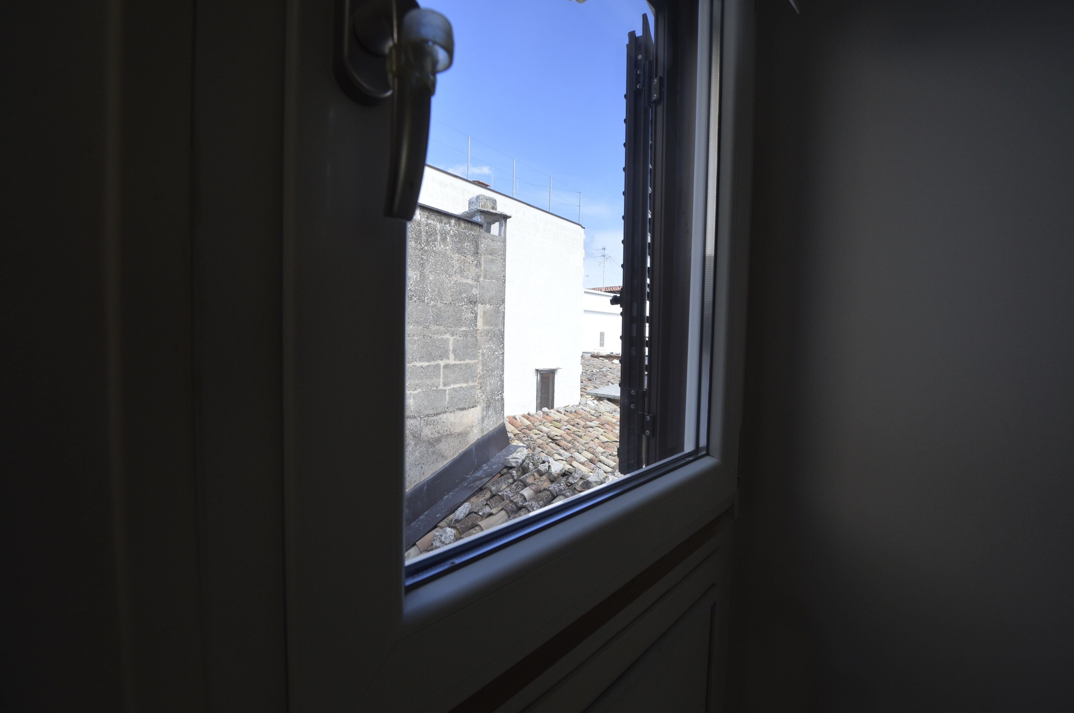 A window with a view of a building's exterior, a door handle, and a partial view of a wall.