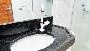 Un baño con un lavabo blanco, un grifo blanco y un espejo sobre el lavabo.
