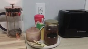 Een keukentrap met een koffiezetapparaat, een broodrooster en potten jam.