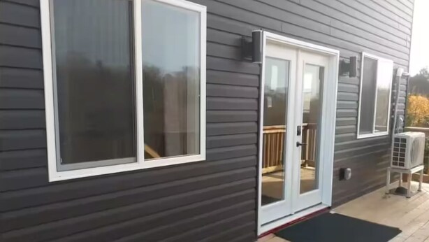 A dark-colored building with a sliding glass door and a small deck area.
