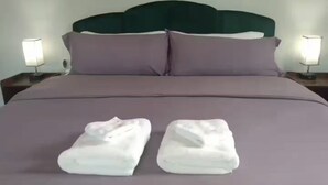 A neatly made bed with two folded white towels on the bedspread.