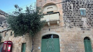 Un edifici de pedra amb una porta verda i una cabina telefònica vermella.