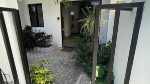 A courtyard with a paved walkway, potted plants, and a door leading to an interior space. - Lavish Studio w Kitchen Downtown (Isla Mujeres)